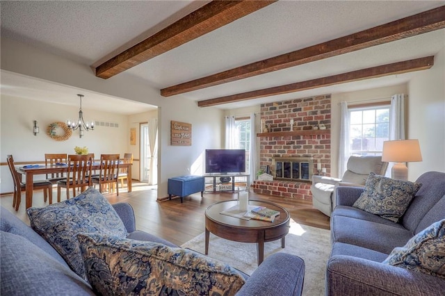 7103 Mastin St, Merriam, KS 66203 - living room featuring a chandelier, wood finished floors, beamed ceiling, a brick fireplace, and a textured ceiling
