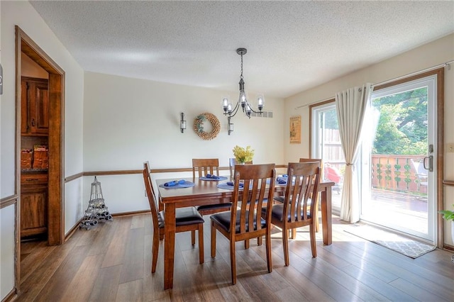 7103 Mastin St, Merriam, KS 66203 - dining space featuring a chandelier, wood finished floors, and a textured ceiling