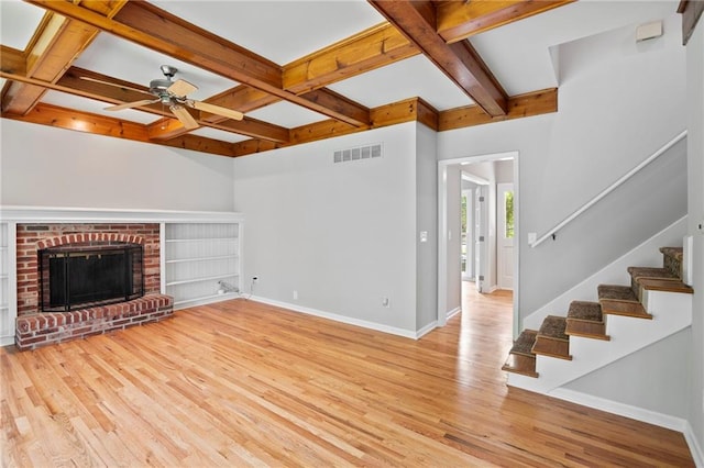 15614 Outlook St, Overland Park, KS 66223 - unfurnished living room with light wood-style flooring, beamed ceiling, stairway, ceiling fan, and a brick fireplace