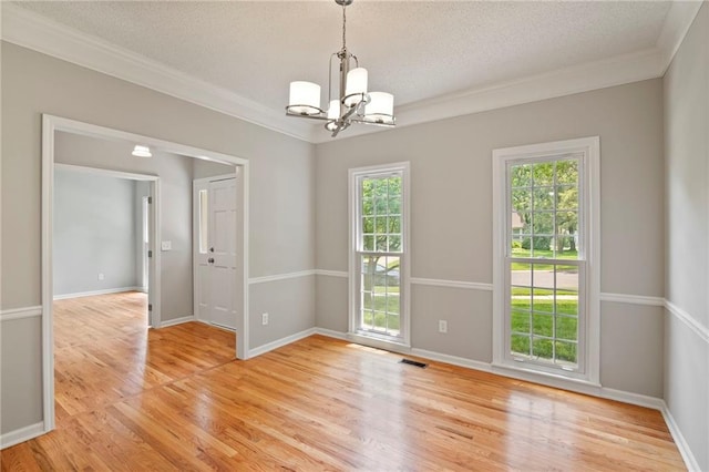 15614 Outlook St, Overland Park, KS 66223 - spare room with a chandelier, ornamental molding, healthy amount of natural light, a textured ceiling, and light wood-style flooring