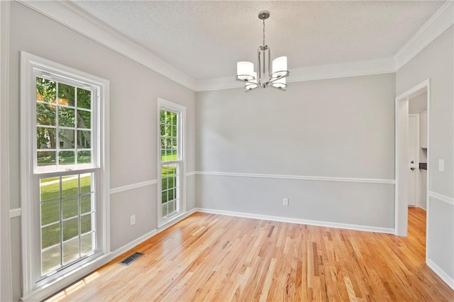 15614 Outlook St, Overland Park, KS 66223 - empty room with a chandelier, light wood-style floors, crown molding, and a textured ceiling
