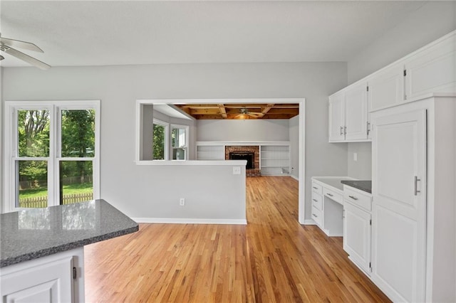 15614 Outlook St, Overland Park, KS 66223 - kitchen with ceiling fan, white cabinetry, light wood-style flooring, a fireplace, and open floor plan