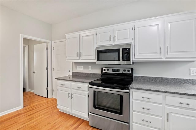 15614 Outlook St, Overland Park, KS 66223 - kitchen featuring stainless steel appliances, dark countertops, light wood-type flooring, and white cabinetry