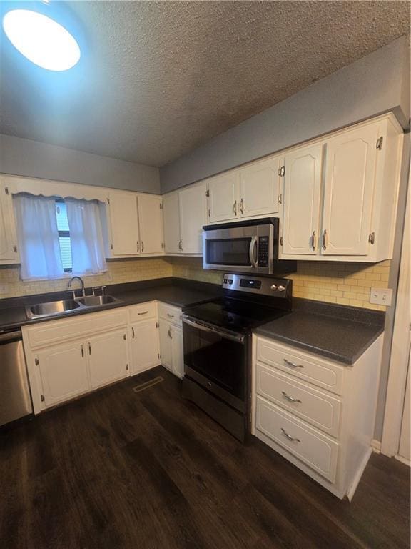 408 Creach St, Warrensburg, MO 64093 - kitchen with appliances with stainless steel finishes, dark countertops, white cabinetry, and a textured ceiling