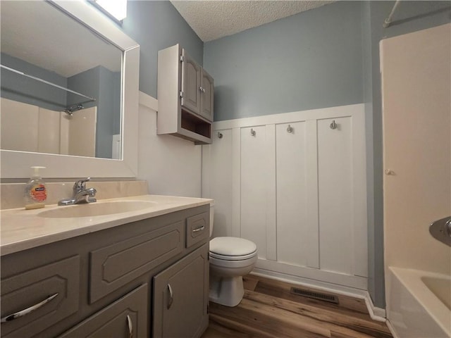 408 Creach St, Warrensburg, MO 64093 - bathroom with wood finished floors, a textured ceiling, vanity, shower / tub combination, and wainscoting