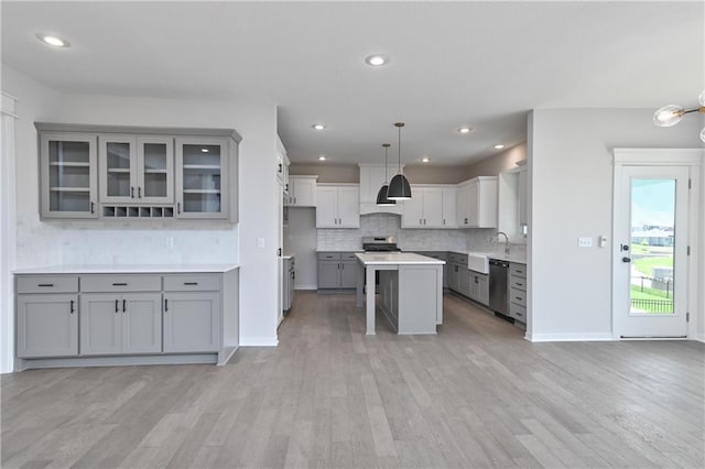 6126 Lewis Dr, Shawnee, KS 66226 - kitchen featuring gray cabinets, stainless steel appliances, a kitchen breakfast bar, backsplash, and light wood-type flooring