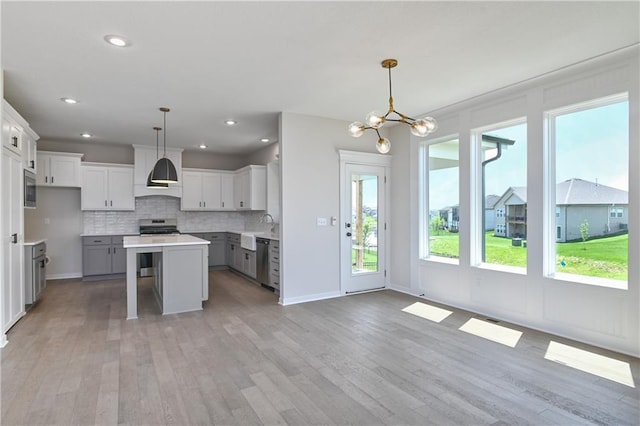 6126 Lewis Dr, Shawnee, KS 66226 - kitchen with stainless steel appliances, light wood-style floors, a center island, a breakfast bar area, and decorative backsplash