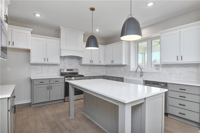 6126 Lewis Dr, Shawnee, KS 66226 - kitchen with stainless steel gas stove, gray cabinetry, wood finished floors, decorative backsplash, and a center island