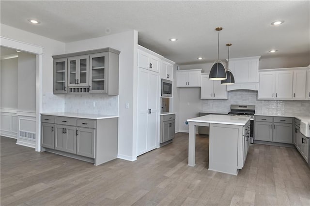 6126 Lewis Dr, Shawnee, KS 66226 - kitchen with gray cabinets, appliances with stainless steel finishes, glass insert cabinets, light wood-style floors, and a center island
