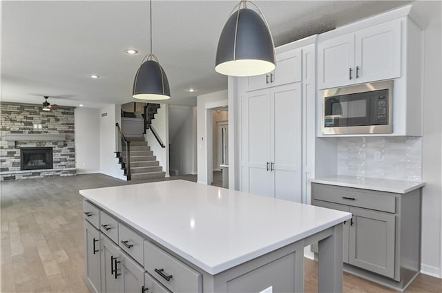 6126 Lewis Dr, Shawnee, KS 66226 - kitchen with stainless steel microwave, gray cabinets, a ceiling fan, light countertops, and light wood-type flooring