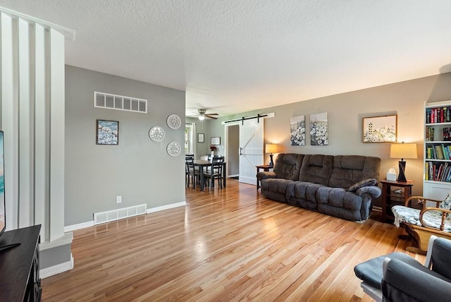 14224 E 36th St, Independence, MO 64055 - living room with a barn door, light wood-type flooring, a textured ceiling, and ceiling fan