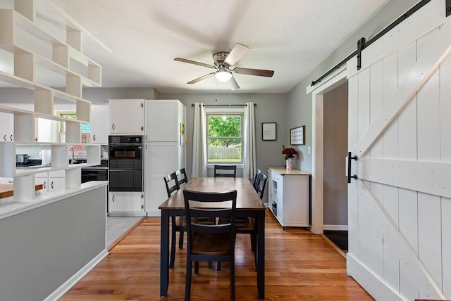 14224 E 36th St, Independence, MO 64055 - dining room featuring a barn door, a ceiling fan, light wood-type flooring, and a textured ceiling
