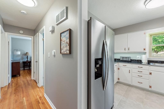 14224 E 36th St, Independence, MO 64055 - kitchen featuring stainless steel fridge, white cabinetry, dark countertops, a textured ceiling, and light wood-style flooring