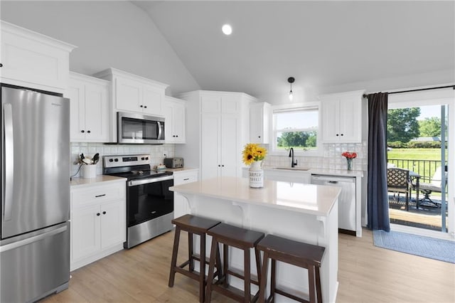 462 SE 90th Rd, Warrensburg, MO 64093 - kitchen with appliances with stainless steel finishes, vaulted ceiling, light countertops, tasteful backsplash, and light wood-style flooring