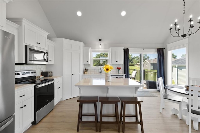 462 SE 90th Rd, Warrensburg, MO 64093 - kitchen featuring appliances with stainless steel finishes, vaulted ceiling, light countertops, a chandelier, and a center island