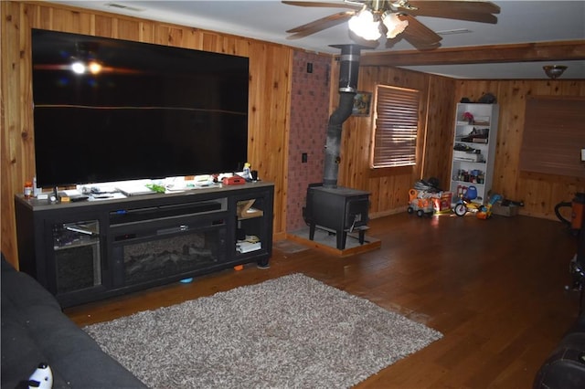 21570 Mclouth Rd, Mc Louth, KS 66054 - living room featuring wooden walls, ceiling fan, a wood stove, and wood finished floors