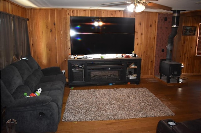 21570 Mclouth Rd, Mc Louth, KS 66054 - living room featuring a ceiling fan, wood walls, wood finished floors, and a wood stove