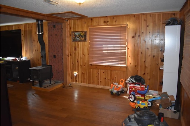21570 Mclouth Rd, Mc Louth, KS 66054 - unfurnished dining area featuring wooden walls, wood finished floors, a wood stove, and a textured ceiling