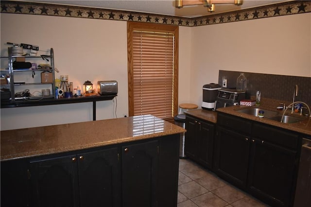 21570 Mclouth Rd, Mc Louth, KS 66054 - kitchen with dark cabinetry, light tile patterned floors, dishwashing machine, and dark stone countertops