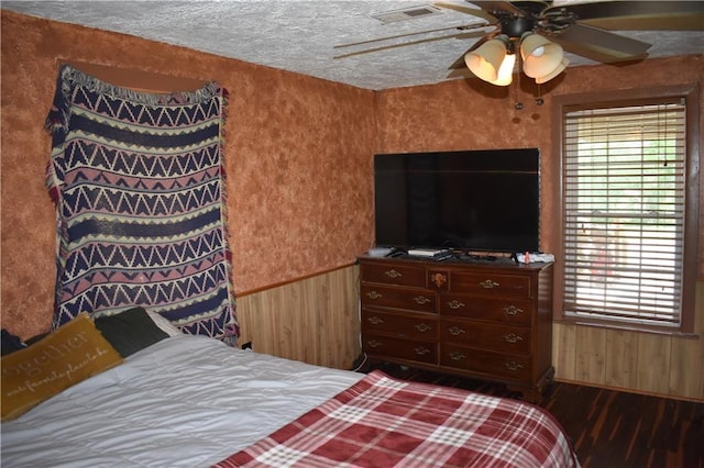 21570 Mclouth Rd, Mc Louth, KS 66054 - bedroom featuring wooden walls, dark wood-type flooring, a wainscoted wall, and ceiling fan