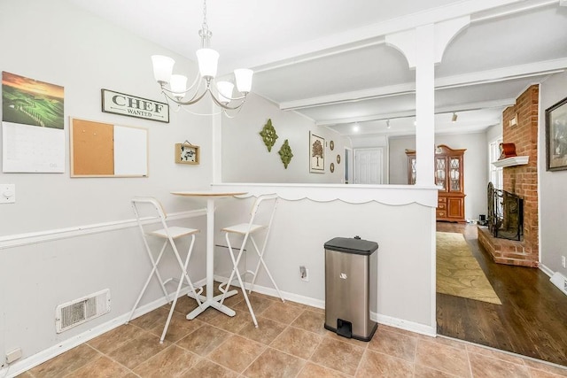 6305 N Bales Ave, Gladstone, MO 64119 - dining room featuring beam ceiling, a chandelier, and a brick fireplace