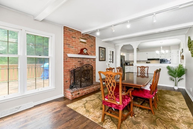 6305 N Bales Ave, Gladstone, MO 64119 - dining area featuring track lighting, dark wood-style floors, a fireplace, a chandelier, and beamed ceiling