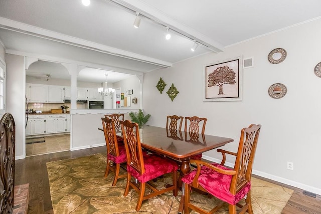 6305 N Bales Ave, Gladstone, MO 64119 - dining area featuring rail lighting, a chandelier, dark wood-type flooring, and arched walkways