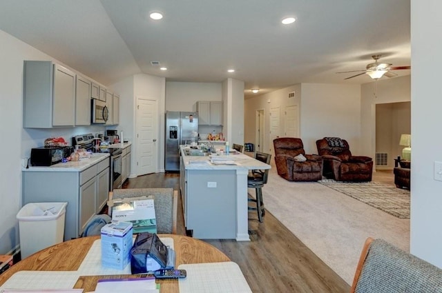 8025 SE 6th Ter, Blue Springs, MO 64014 - kitchen with stainless steel appliances, gray cabinets, a kitchen bar, an island with sink, and light countertops