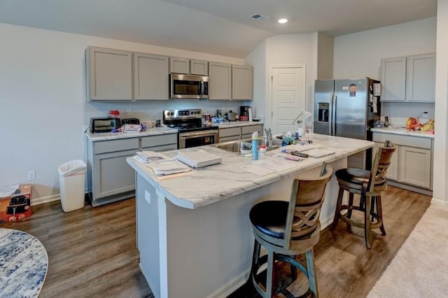 8025 SE 6th Ter, Blue Springs, MO 64014 - kitchen with stainless steel appliances, gray cabinets, wood finished floors, a breakfast bar, and light countertops