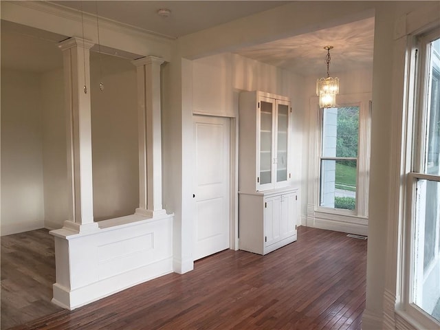 605 Hall St, Saint Joseph, MO 64501 - unfurnished dining area with dark wood-style floors, ornate columns, and a chandelier