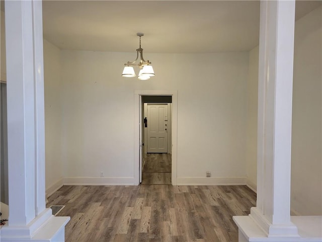 605 Hall St, Saint Joseph, MO 64501 - unfurnished dining area featuring wood finished floors, decorative columns, and a chandelier