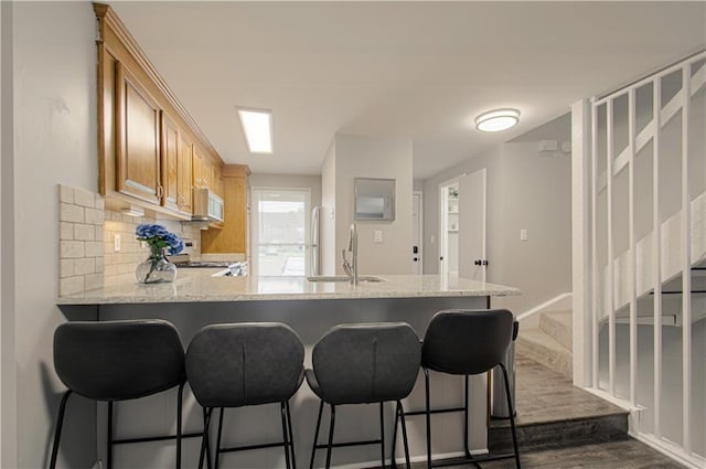 12131 W 82nd Ter, Lenexa, KS 66215 - kitchen featuring white microwave, range, a peninsula, dark wood-type flooring, and decorative backsplash