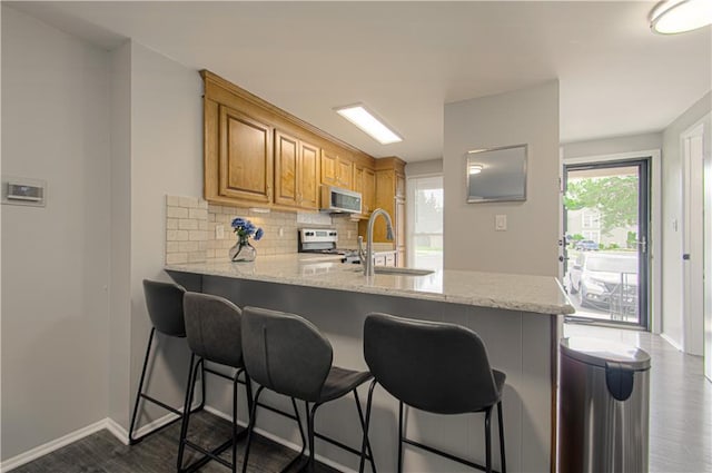 12131 W 82nd Ter, Lenexa, KS 66215 - kitchen featuring stainless steel range oven, dark wood-type flooring, decorative backsplash, and a peninsula