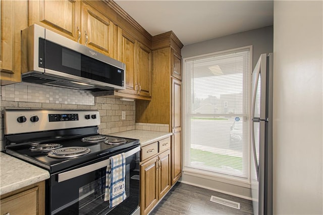 12131 W 82nd Ter, Lenexa, KS 66215 - kitchen featuring appliances with stainless steel finishes, light countertops, decorative backsplash, dark wood finished floors, and brown cabinetry