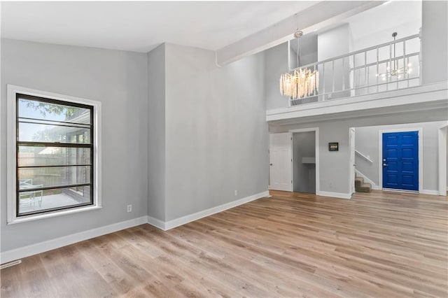 10312 W 48th Ter, Shawnee, KS 66203 - unfurnished living room with stairway, a chandelier, wood finished floors, and a towering ceiling