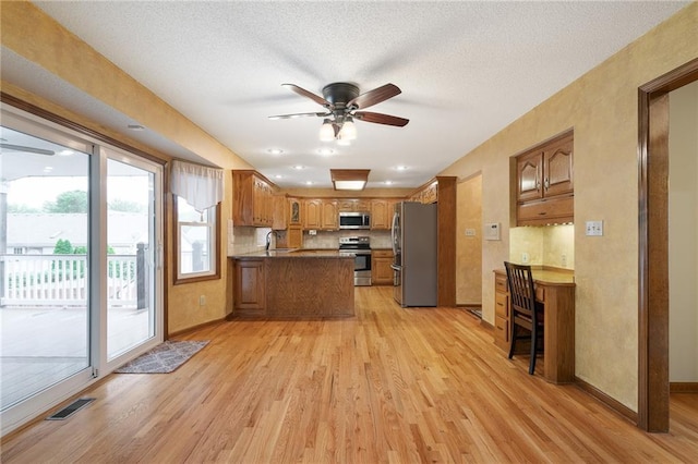 18807 E 34th St, Independence, MO 64057 - kitchen featuring appliances with stainless steel finishes, a peninsula, light wood finished floors, ceiling fan, and brown cabinets