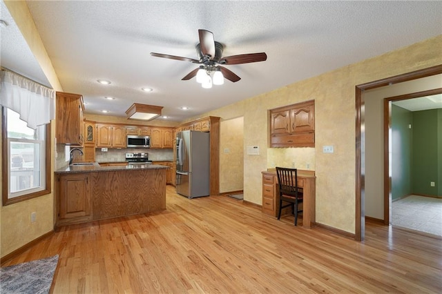 18807 E 34th St, Independence, MO 64057 - kitchen featuring stainless steel appliances, a peninsula, light wood-type flooring, ceiling fan, and dark countertops