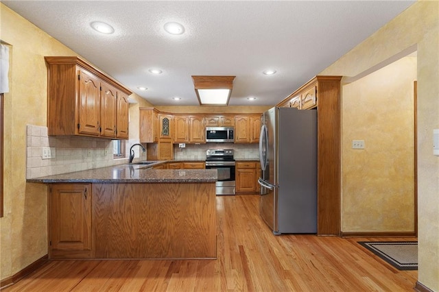 18807 E 34th St, Independence, MO 64057 - kitchen with appliances with stainless steel finishes, a peninsula, light wood-style floors, brown cabinetry, and backsplash
