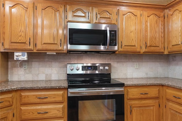 18807 E 34th St, Independence, MO 64057 - kitchen featuring stainless steel appliances, decorative backsplash, brown cabinetry, and dark stone counters