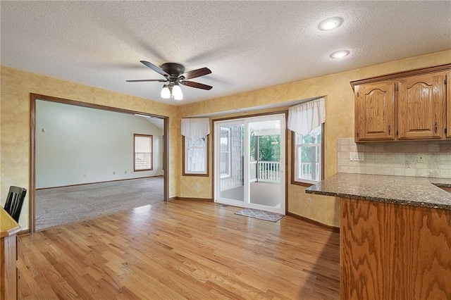 18807 E 34th St, Independence, MO 64057 - kitchen featuring light wood-style floors, a ceiling fan, dark stone counters, a textured ceiling, and open floor plan