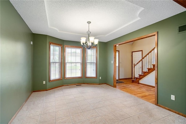 18807 E 34th St, Independence, MO 64057 - empty room featuring a textured ceiling, a chandelier, a raised ceiling, stairs, and light tile patterned floors