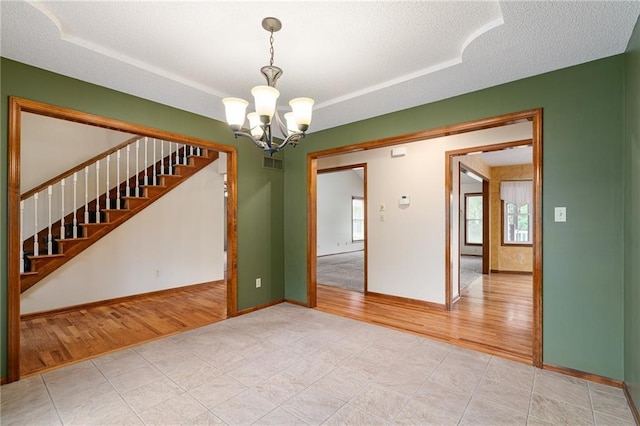 18807 E 34th St, Independence, MO 64057 - unfurnished room with a chandelier, light wood-style floors, a tray ceiling, stairway, and a textured ceiling