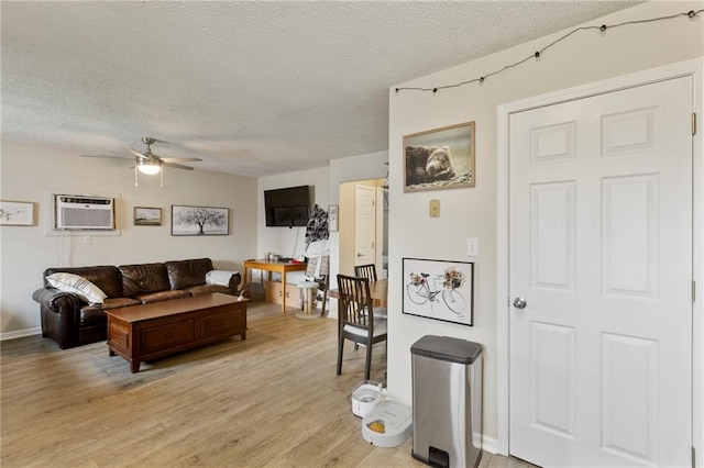 301-A N 3rd St, Odessa, MO 64076 - living room featuring a textured ceiling, a wall mounted air conditioner, ceiling fan, and light wood-style flooring
