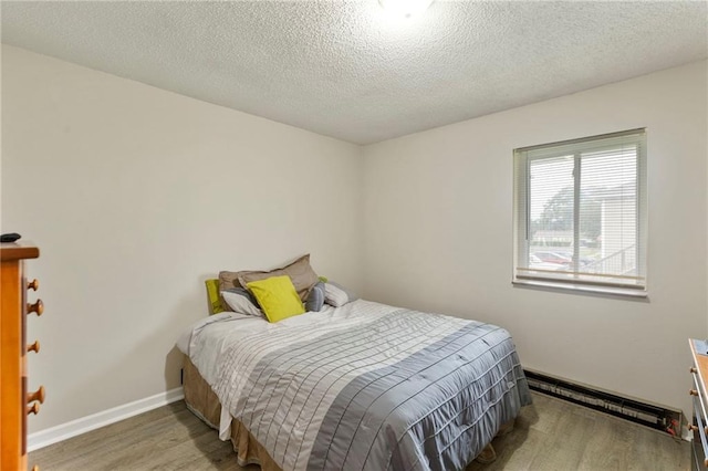 301-A N 3rd St, Odessa, MO 64076 - bedroom with a baseboard radiator, wood finished floors, and a textured ceiling
