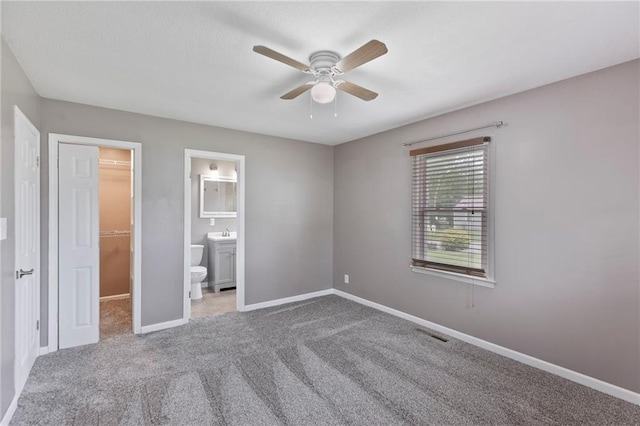 801 NE 67th Ter, Gladstone, MO 64118 - unfurnished bedroom featuring a walk in closet, carpet flooring, ensuite bath, ceiling fan, and a closet
