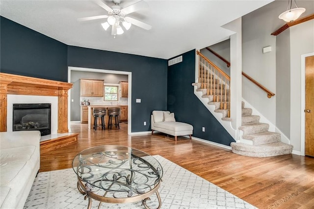 18300 Oak St, Gardner, KS 66030 - living area with wood finished floors, stairs, a ceiling fan, and a glass covered fireplace