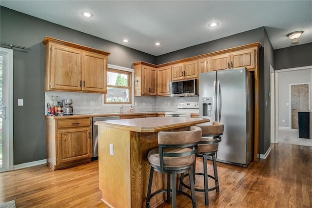 18300 Oak St, Gardner, KS 66030 - kitchen with stainless steel appliances, a kitchen island, light wood-style flooring, decorative backsplash, and recessed lighting