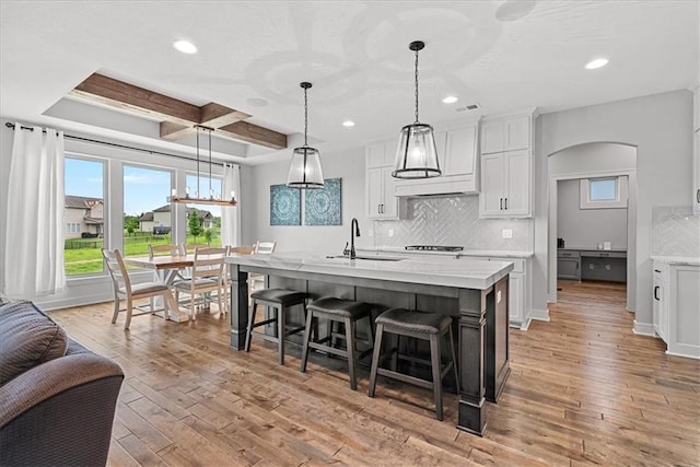 1013 Old Hickory Rd, Greenwood, MO 64034 - kitchen with recessed lighting, light wood-style flooring, arched walkways, white cabinetry, and backsplash