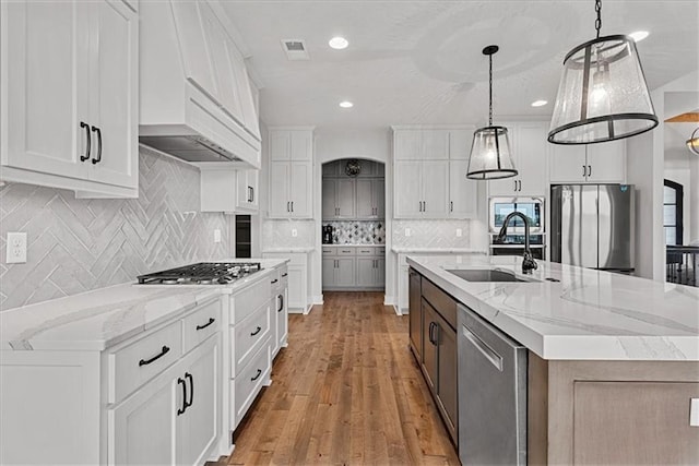 1013 Old Hickory Rd, Greenwood, MO 64034 - kitchen featuring appliances with stainless steel finishes, a large island, white cabinets, light wood-style flooring, and tasteful backsplash