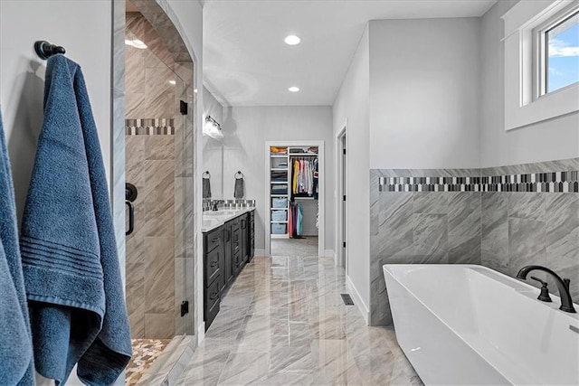 1013 Old Hickory Rd, Greenwood, MO 64034 - bathroom with a stall shower, a freestanding tub, a spacious closet, tile walls, and marble tiled floors